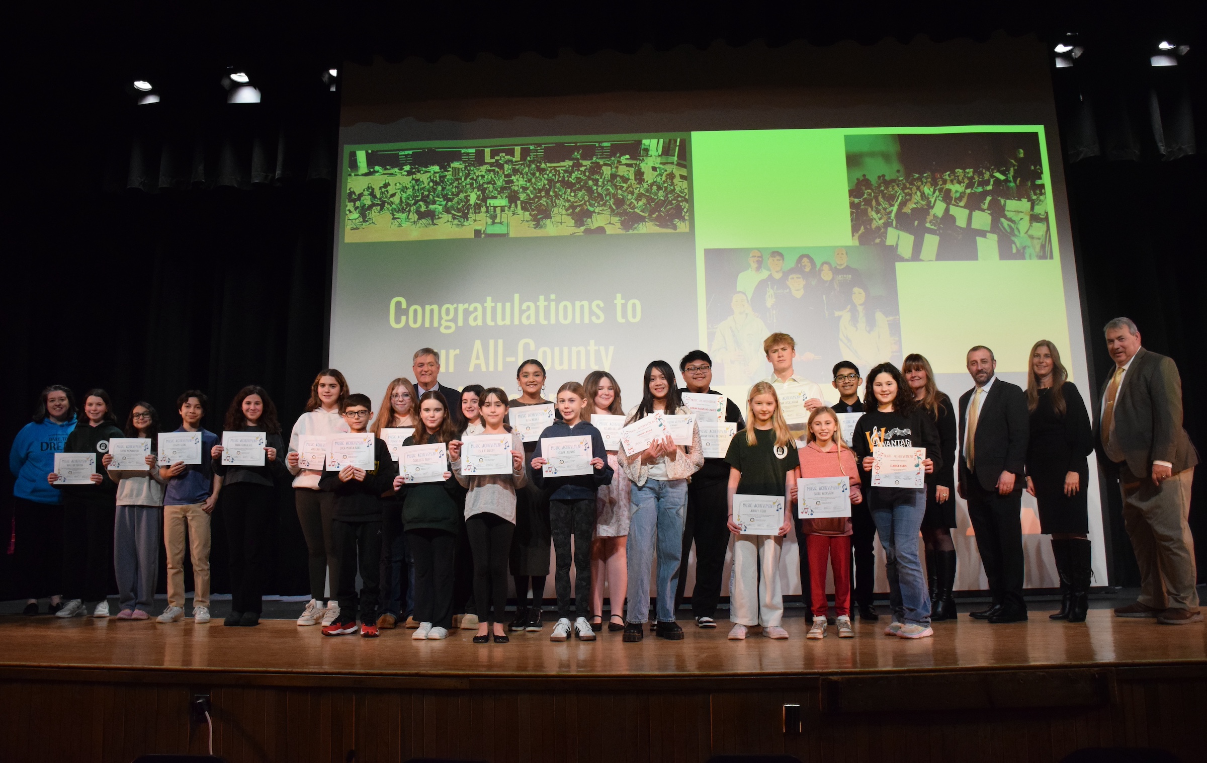 kids standing on stage holding certificates